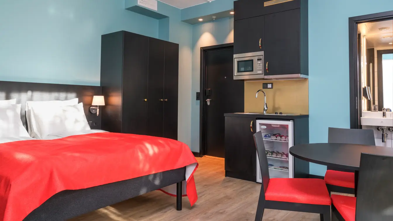 Dobbeltseng, skap, minikjøkken og kjøkkenbord på 2 roms leilighet på Thon Hotel Linne