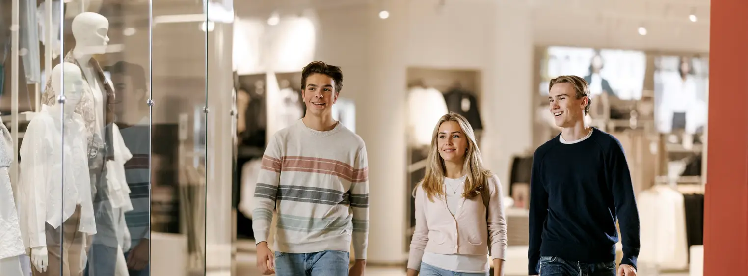 To gutter og en jente går gjennom en gang i et kjøpesenter