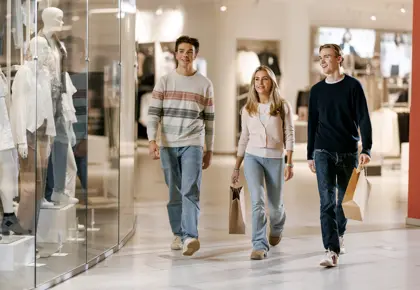 To gutter og en jente går gjennom en gang i et kjøpesenter