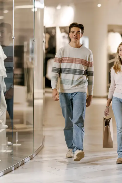 To gutter og en jente går gjennom en gang i et kjøpesenter