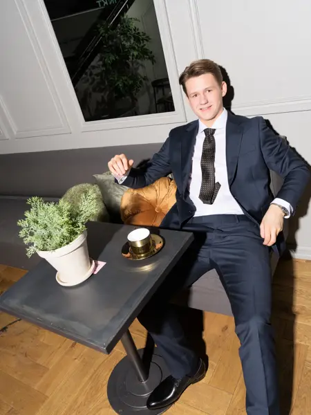 Gutt i blå dress som sitter ved et bord