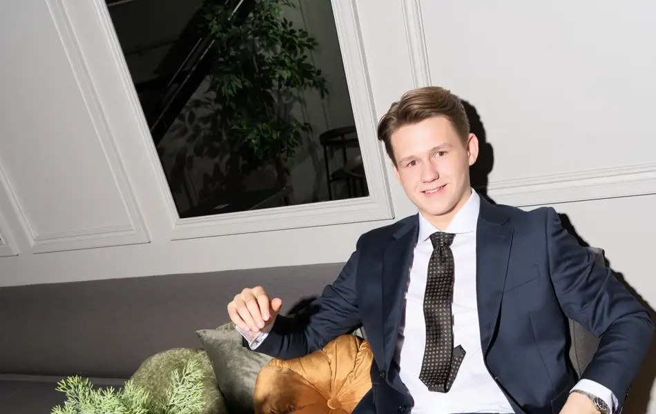 Gutt i blå dress som sitter ved et bord