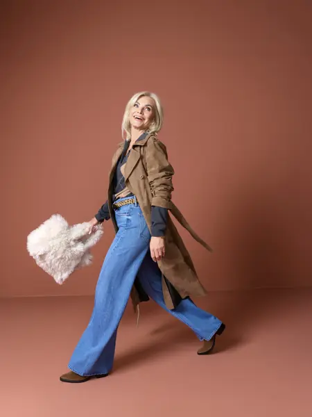 Marianne med brun trench, jeans, genser og lys veske.
