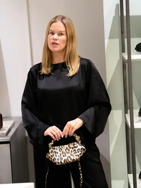 Dame med sort blank kjole og liten leopardveske.