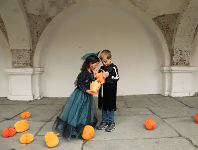 To barn som ser i en godteribøtte til halloween