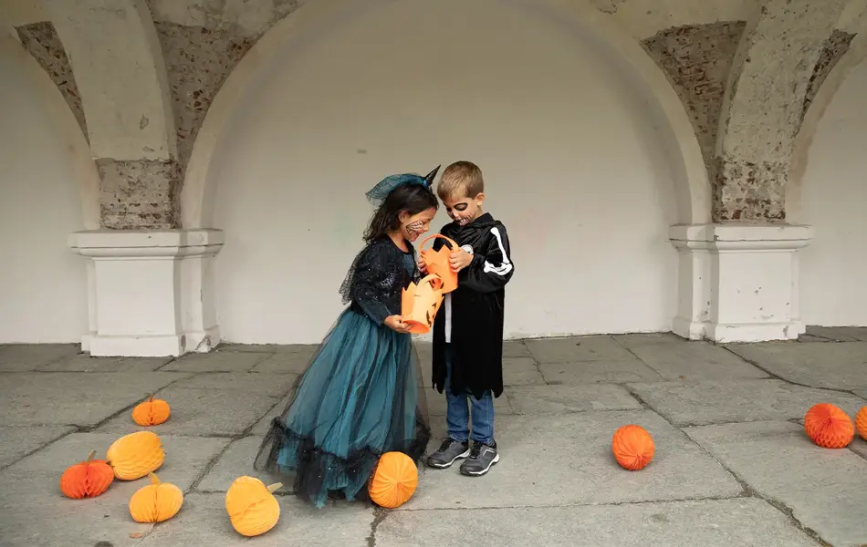 To barn som ser i en godteribøtte til halloween