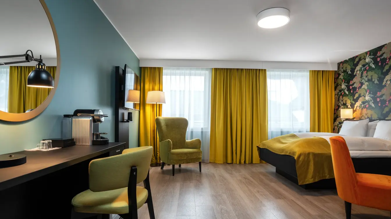 Businessrom hos Thon Hotel Bristol Bergen med skrivepult, TV, store vindusflater, dobbeltseng, lenestoler og Nespresso-maskin. Gulvet er parkettbelagt.