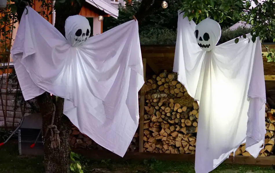 Hjemmelaget spøkelser av laken som henger fra trær