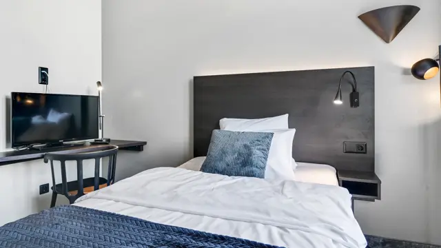 Enkeltseng, hvite vegger, TV, skrivebord, stol. 