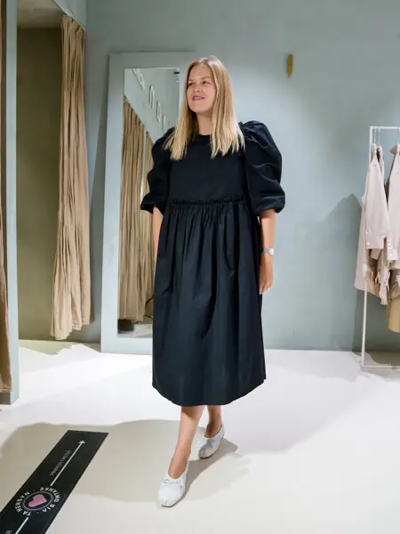 Jente med blondt hår, har på seg en lang sort kjole