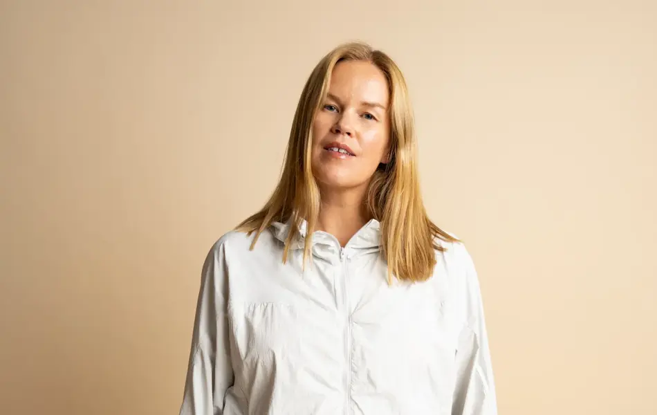 damemodell i lysegrå tynn treningsjakke og skjørt, og stråveske