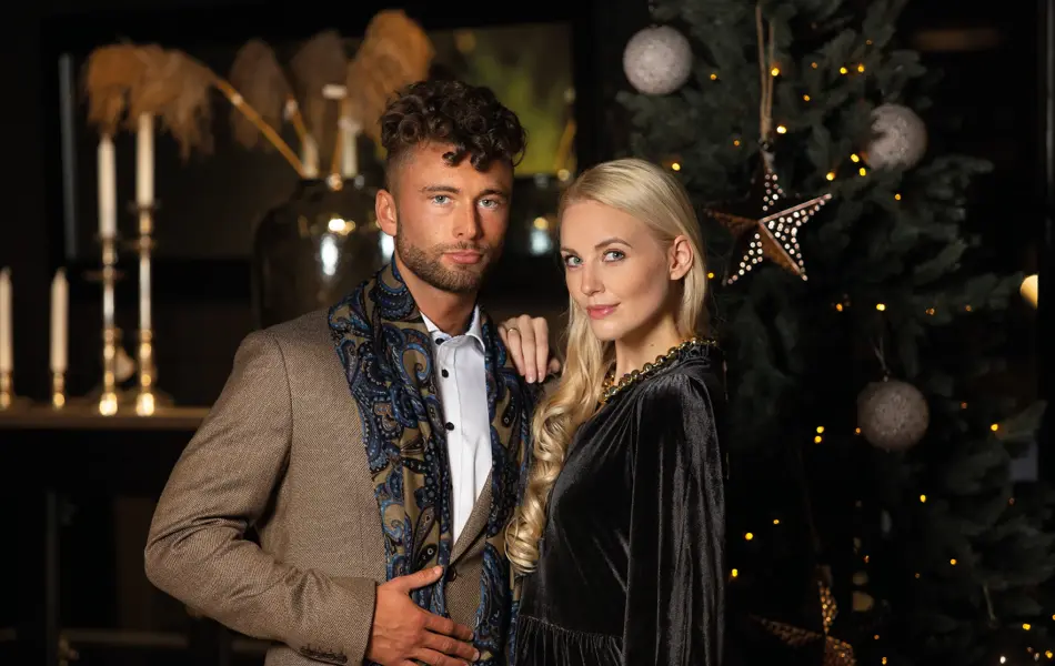 Par i pentøy foran glamorøst juletre