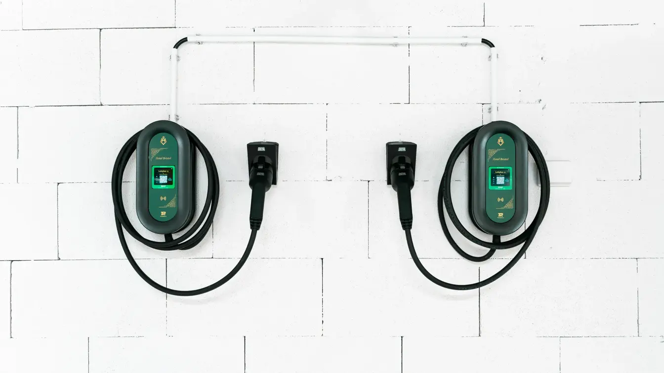 To ladekabler til el-bil henger på hvit vegg.