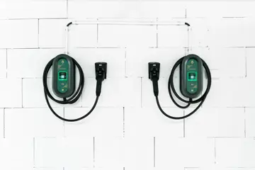 To ladekabler til el-bil henger på hvit vegg.