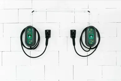 To ladekabler til el-bil henger på hvit vegg.