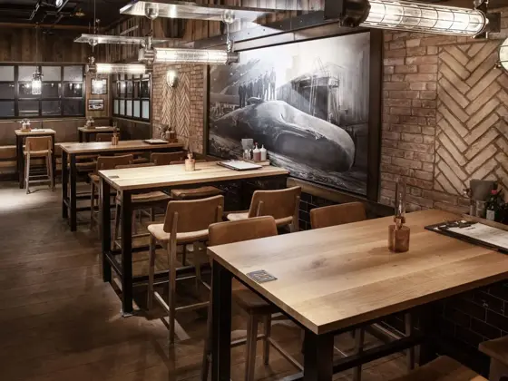 restaurant med flere sitteplasser av tre og et stort maleri med hval