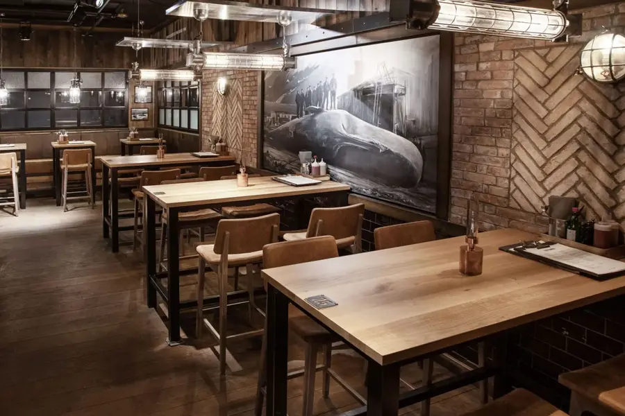restaurant med flere sitteplasser av tre og et stort maleri med hval