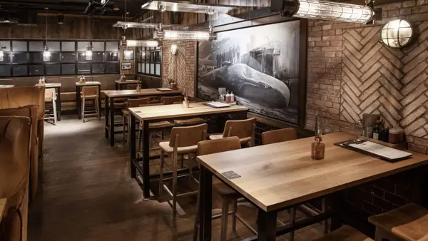 restaurant med flere sitteplasser av tre og et stort maleri med hval