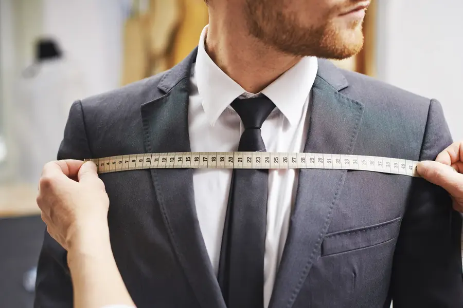 Tailor measuring front of businessman jacket