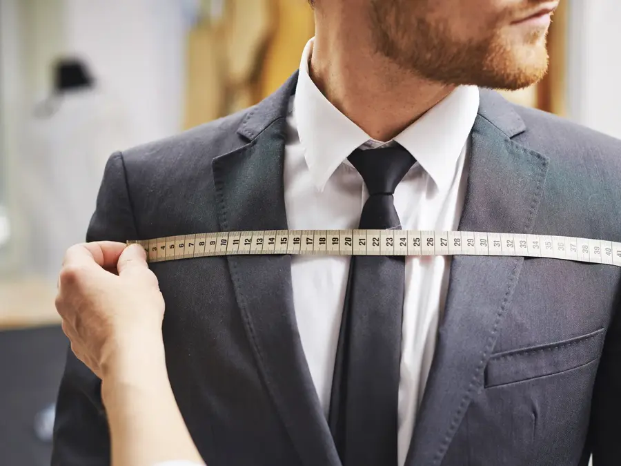 Tailor measuring front of businessman jacket