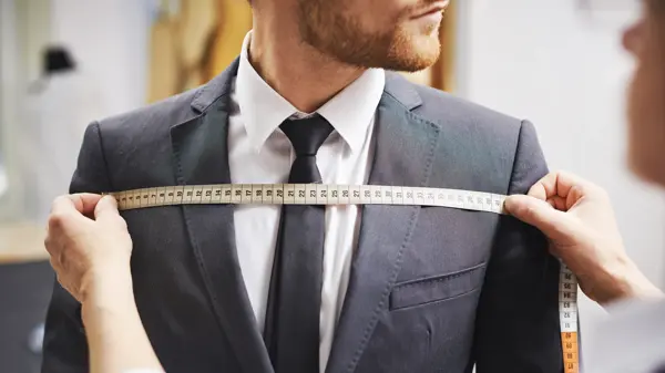 Tailor measuring front of businessman jacket