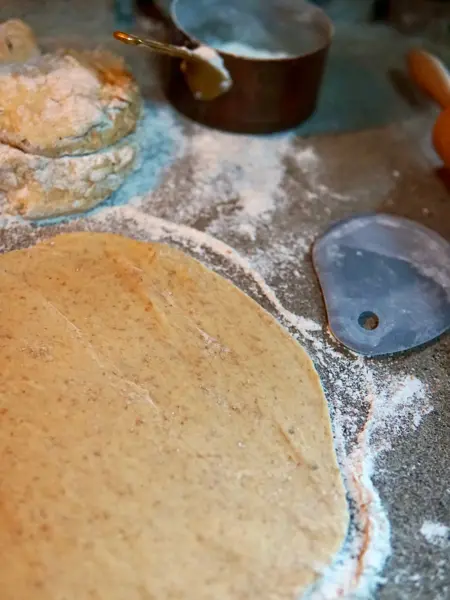 deigen er kjevlet ut på en benk, omringet av mel