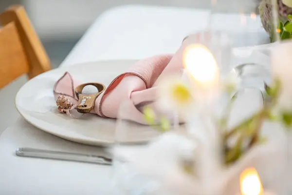 Langbord dekker til gjester med rosa servietter og grønn naturlig dekorasjon