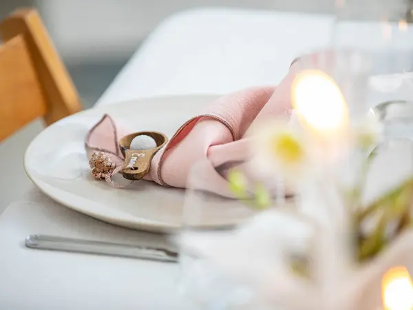 Langbord dekker til gjester med rosa servietter og grønn naturlig dekorasjon