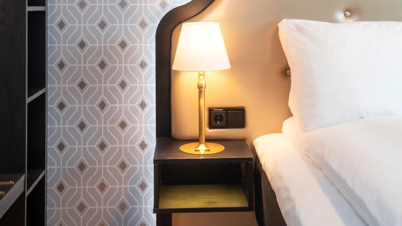 Seng meg sengegavl og mønstret sølvtapet i junior suite på Thon Hotel Cecil