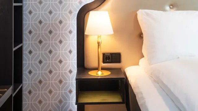 Seng meg sengegavl og mønstret sølvtapet i junior suite på Thon Hotel Cecil