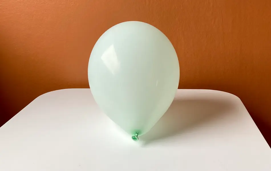 Oppblåst ballong som ligger på et bord med oransje bakgrunn