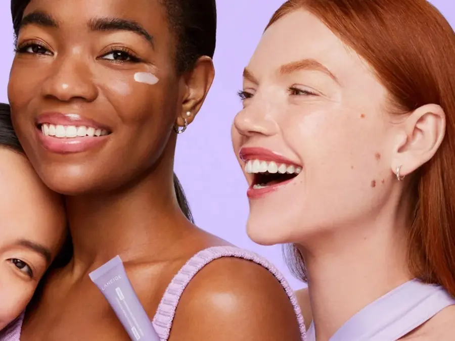 Tre damer som smiler med lillebakgrunn