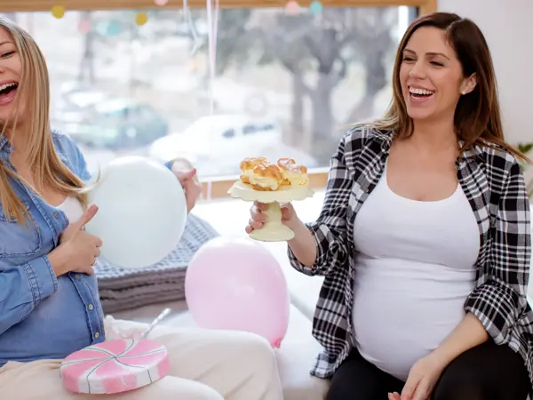 Friends laughing on babyshower, holding plate with dessert
