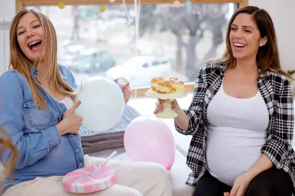Friends laughing on babyshower, holding plate with dessert