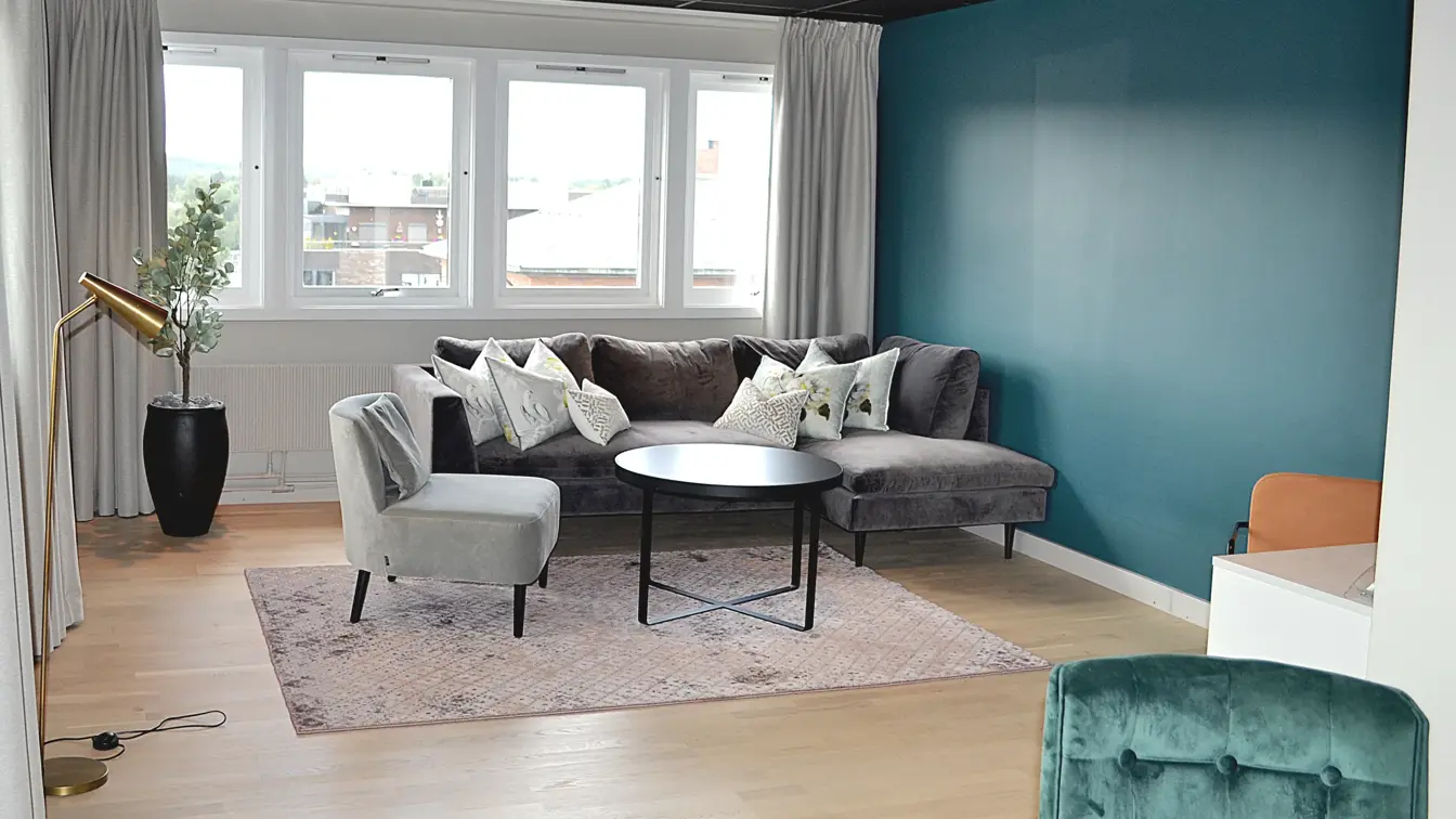 Blå vegg stort vindu, grå stol, sofa, plante, lampe, teppe