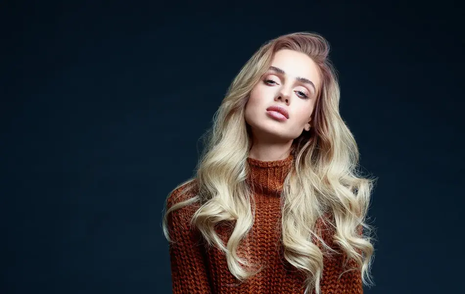 Dame med brun ullgenser og brun- og hvitprikkede skjørt poserer på stol