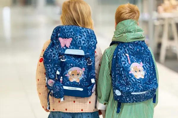 Jente og gutt med ryggen til kamera med blå skolesekker.