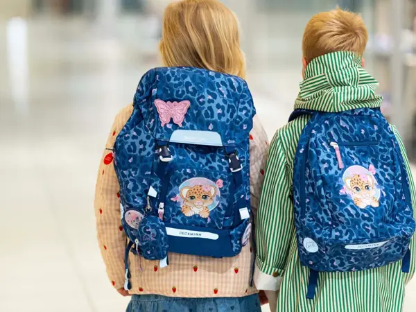 Jente og gutt med ryggen til kamera med blå skolesekker.