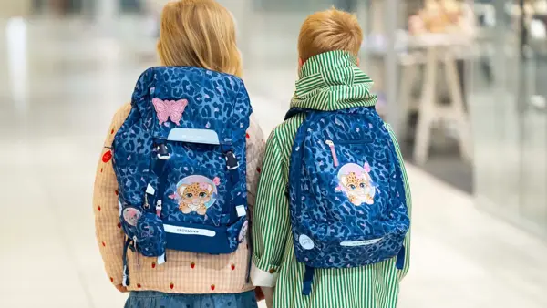 Jente og gutt med ryggen til kamera med blå skolesekker.