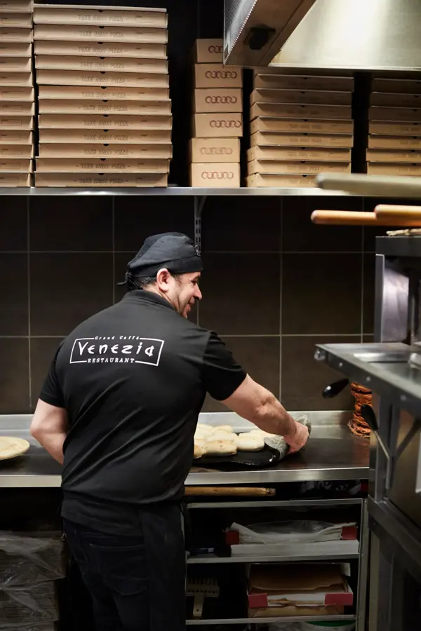 kokk som lager pizza hos grand caffe venezia
