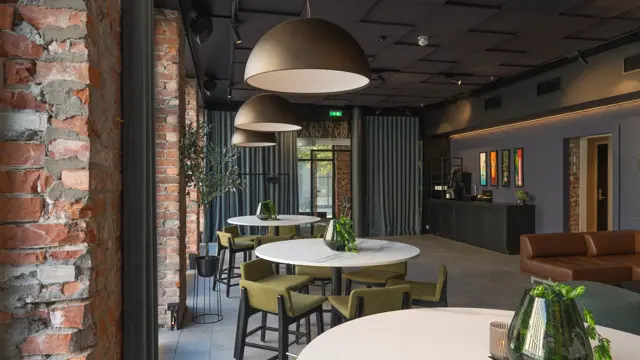 Lounge i rustikk stil med flere runde høybord og høye stoler rundt. 