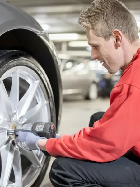 Mann skrur på bildekk