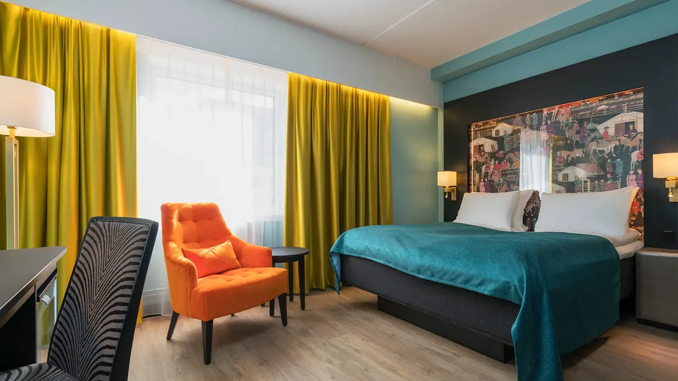 Dobbeltseng, orange lenestol og skrivebord i dobeltrom på Thon Hotel Linne