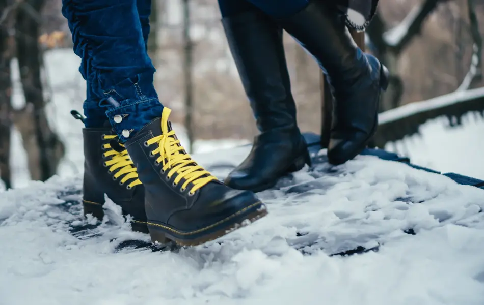 Women legs wearing boots standing on snow.