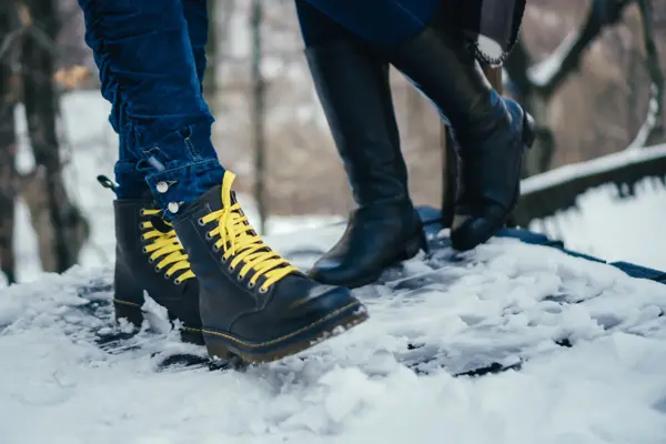 Women legs wearing boots standing on snow.