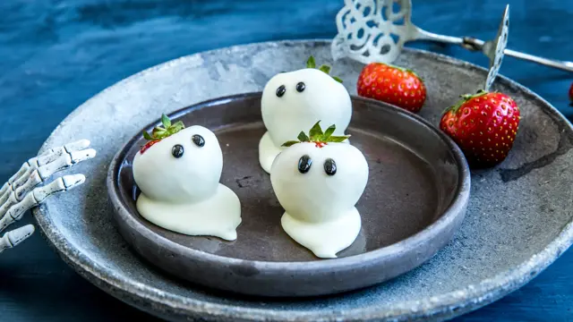 Tre jordbær dekket i hvit sjokolade med ørne