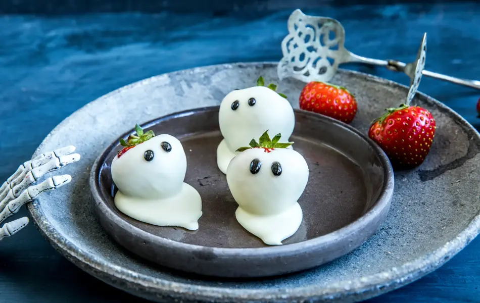 Tre jordbær dekket i hvit sjokolade med ørne