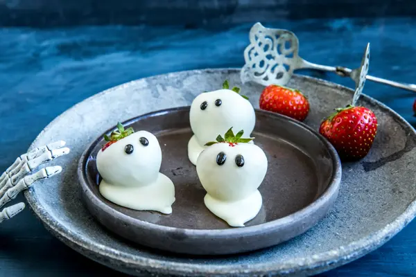 Tre jordbær dekket i hvit sjokolade med ørne