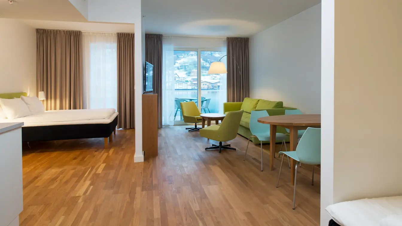 Dobbeltseng, sofa og bord med flere sitteplasser på ettroms leilighet  på Thon Hotel Sandven