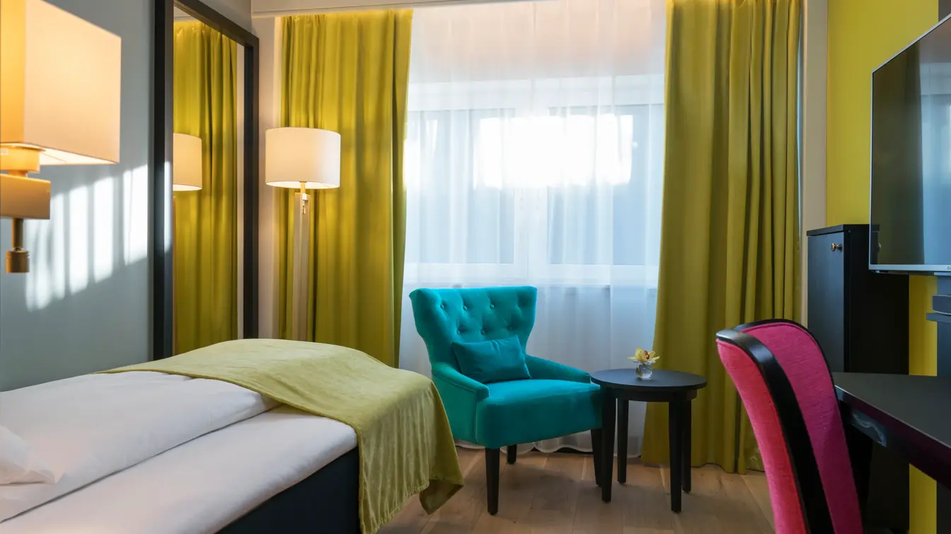 Enkeltseng med sengeteppe, TV, godstol, skrivepult med stol i Single room på Thon Hotel Arendal i Arendal sentrum